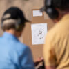 Student has shot a nice target, with Bryan and student talking about handgun technique in the foreground.