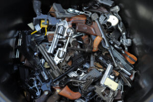 Lots and lots of handguns piled in a container.